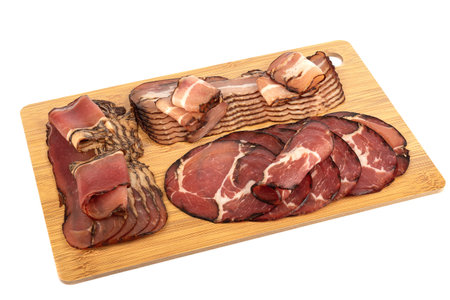 Assorted chopped pork brisket, neck and prosciutto on a wooden cutting board.の写真素材