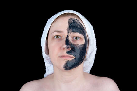 Young woman with cosmetic scrub mask on half of her face. Facial skin care.の写真素材