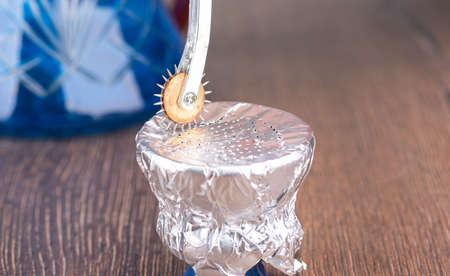 Puncture the foil with a rotating wheel punch on the hookah tobacco bowl. Hookah preparation.
