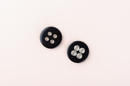 Two black plastic buttons on both sides with metal inserts in the holes.