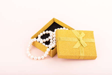 Pearl beads in a gift box on a pink background.の写真素材