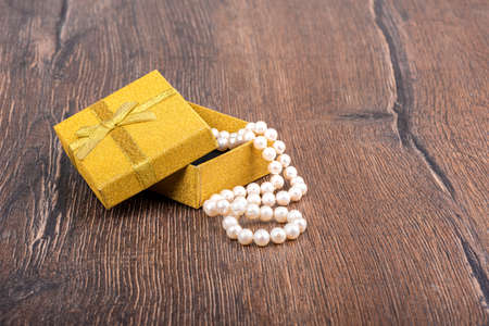 A necklace of pearl beads in a gift box on a wooden background.の写真素材