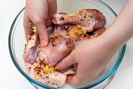 A woman mixes pieces of chicken with spices. Marinating chicken.の写真素材