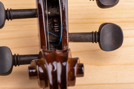 Close-up of fastening the strings in the tuning hole of the violin. Top view.