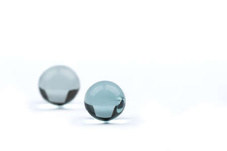 Two glass balls on a white background with space for text, the far ball is blurred. Selective focus on the first glass ball.の写真素材