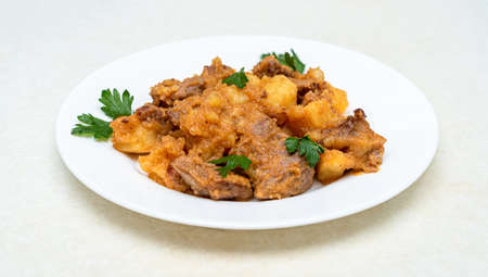 Roast pork with potatoes in gravy garnished with parsley leaves.