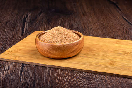 Wooden bowl with brown cane sugar on a wooden background.の写真素材