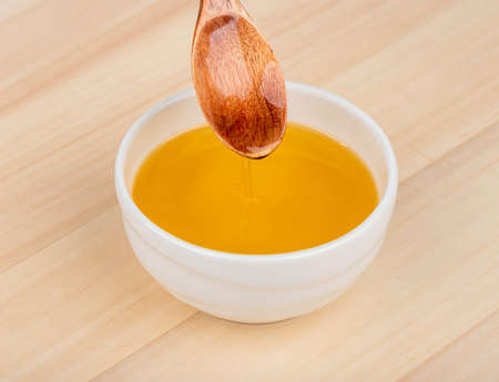 White bowl with sunflower oil on a wooden background.の写真素材