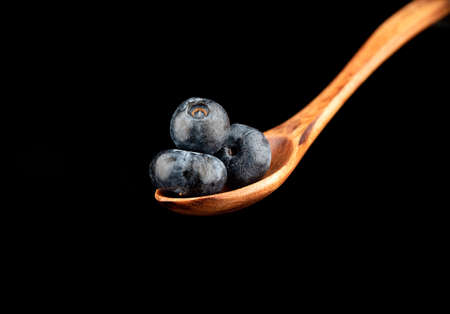Wooden spoon with blueberries on a black background. copyspace.の写真素材