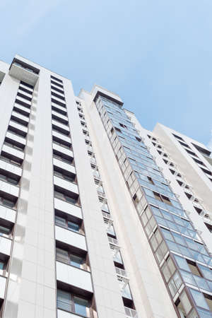 Bottom view of the facade of a multi-storey building with glazed balconies and places for air...