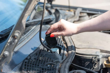 A woman's hand opens the lid of the tank to fill the car's windshield wiper. close up.の写真素材