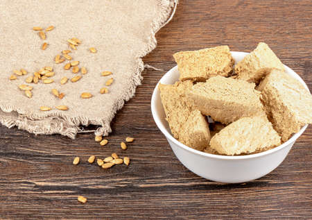 Sunflower seeds on coarse burlap and chopped sunflower halva in a white porcelain bowl. Delicious oriental sweetness halva from sunflower seeds.の写真素材