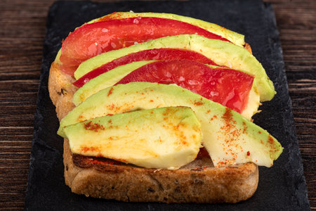 Grain bread sandwich with slices of tomato and avocado and coarse salt. close up.の写真素材