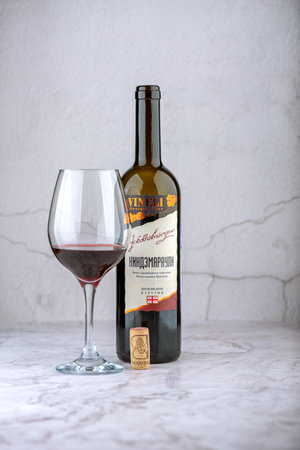 Moscow, Russia: November 21, 2022: Glass of wine and a bottle of Kindzmarauli semi-sweet Georgian wine. The inscription in Russian: Kindzmarauli ordinary wine produced in Georgia.のeditorial素材