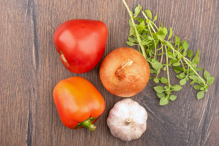 Tomato, garlic, pepper, onion and green basil leaves are the ingredients of tomato puree soup. Wooden background, copy space.の写真素材