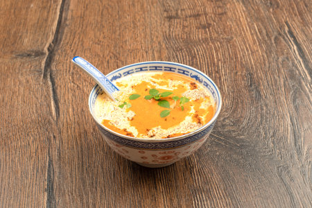 Autumn tomato puree soup in a plate with a spoon on a wooden background. Copy space.の写真素材