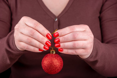 Young woman in a jumper holds a Christmas red toy ball in her arms.の写真素材