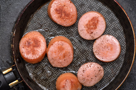 Top view of pieces of sausage fried in vegetable oil in a frying pan. Home cooking.の写真素材