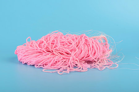 A bunch of pink beads strung on fishing lines lie on a blue background. Copy space.の写真素材