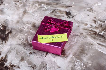 Gift box with a Merry Christmas note on a textured background.