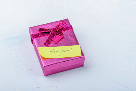 Golden gift box with a note on a light background.