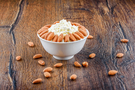 Almonds on a bowl with cottage cheese and on a wooden background.の写真素材