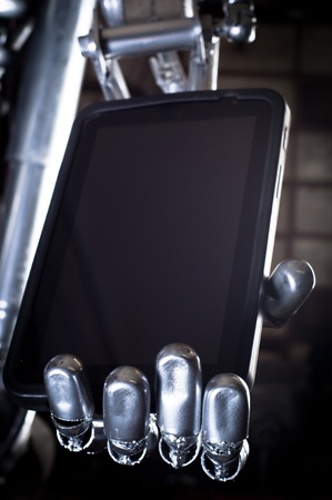 Robot hand holding tablet pc against dark backgroundのeditorial素材