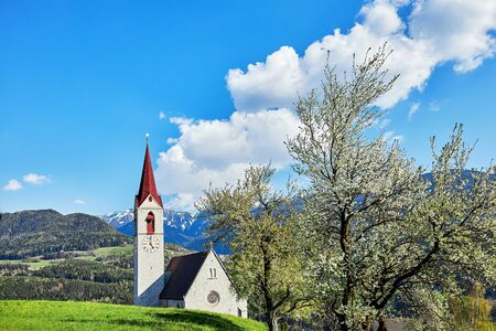 The parish church Maria Himmelfahr in Feldthurns in the middle of the mountain landscape in South Tyrolの写真素材