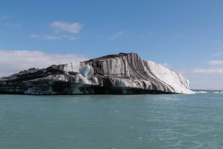Iceberg with visible ash layers in glacier lagoon in icelandの写真素材
