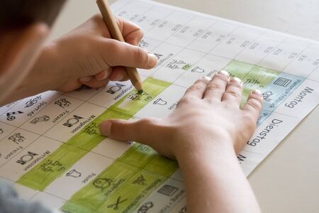 A Pupil coloring a time table, showing his new daily routineの写真素材