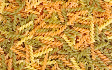 Uncooked pasta (Fusilli) in different colour as backgroundの写真素材