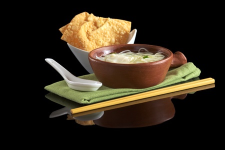 Chinese noodle soup with deep-fried wonton appetizer, ceramic spoon and chopsticks (Selective Focus,...