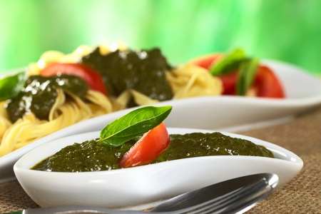 Fresh pesto made of basil and garlic garnished with fresh basil leaf and tomato slice (Selective Focus, Focus on the basil leaf)の写真素材