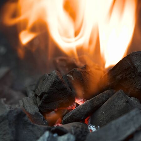 Burning charcoal with orange-colored flame and glow (Selective Focus, Focus on the front of the...