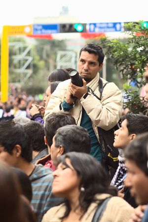 LIMA, PERU - JULY 21, 2013  Unidentified young man with a dslr camera on the Wong Parade in Miraflores on July 21, 2013 in Lima, Peru  The Parade  Gran Corso de Wong  is a traditional parade to celebrate the Peruvian national holiday which is on July 28-2のeditorial素材