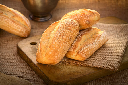 Fresh ciabatta buns on wooden board photographed with natural light (Selective Focus, Focus on the...