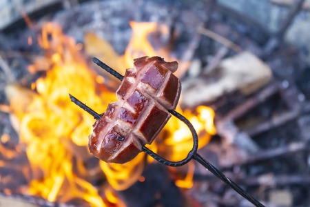 Sausages baking over camp fire. Summer party with friends.の写真素材