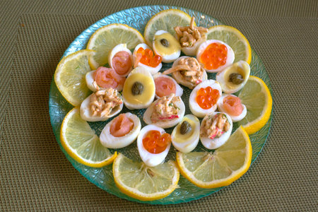 Quail eggs stuffed with seafood and mayonnaise from their yolks with sliced lemons.の写真素材