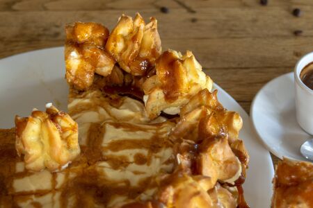 Cake profiteroles with caramel glaze,cream and chocolate. Closeup