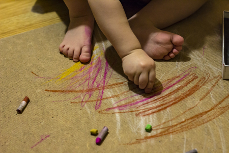 A child paints a pastel on the floorの写真素材
