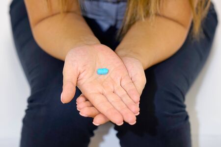 Depressed or ill woman holding pills in her hand, white background.の写真素材