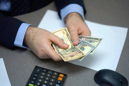 Businessman reviewing and signing agreement contract paper with his partner counting money.