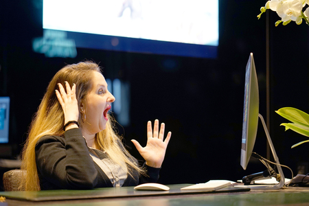 Hotel manager. A woman-reception shocked sitting in front of the monitor of computer. Funny face expression emotion feelings problem perception reaction, stress, fearの写真素材