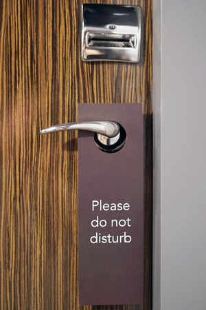 Do Not Disturb sign hang on door knob. Do No Disturb sign at hotel room door. Close-upの写真素材