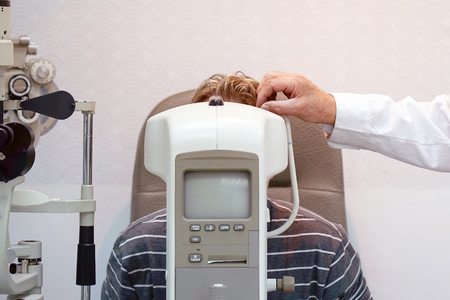Man ophthalmologist examining patient man with optometrist trial frame. Male patient to check vision in ophthalmological clinicの写真素材