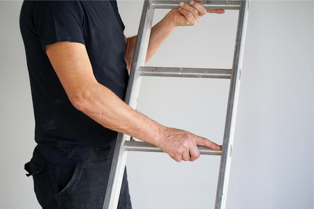 An electrician holds an aluminum ladder. The builder carries an aluminum stepladder. Worker of the plant with aluminum rung ladderの写真素材