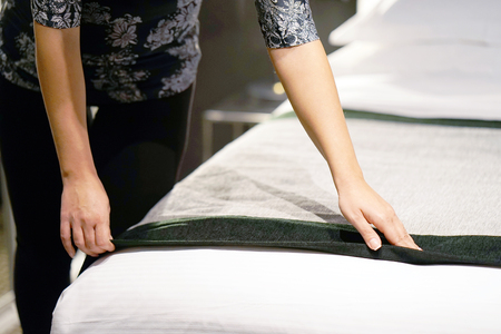 Maid making bed in hotel room.の写真素材