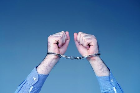 Close-up. Arrested man handcuffed hands at the back. Prisoner or arrested terrorist, close-up of hands in handcuffs, selective focus.の写真素材