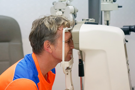 health care, medicine, people, eyesight and technology concept - man checks his vision on the...