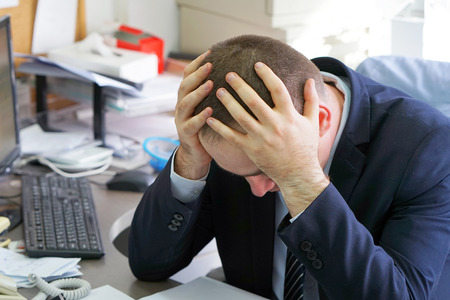 Businessman Suffering From Headache Sitting In Front Of Computer. Body And Health Care Concept.の写真素材
